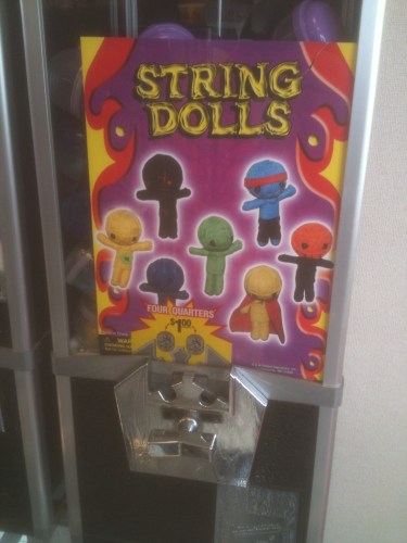 Photo of a quarter machine at Steak 'N Shake that dispenses string dolls that look like voodoo dolls