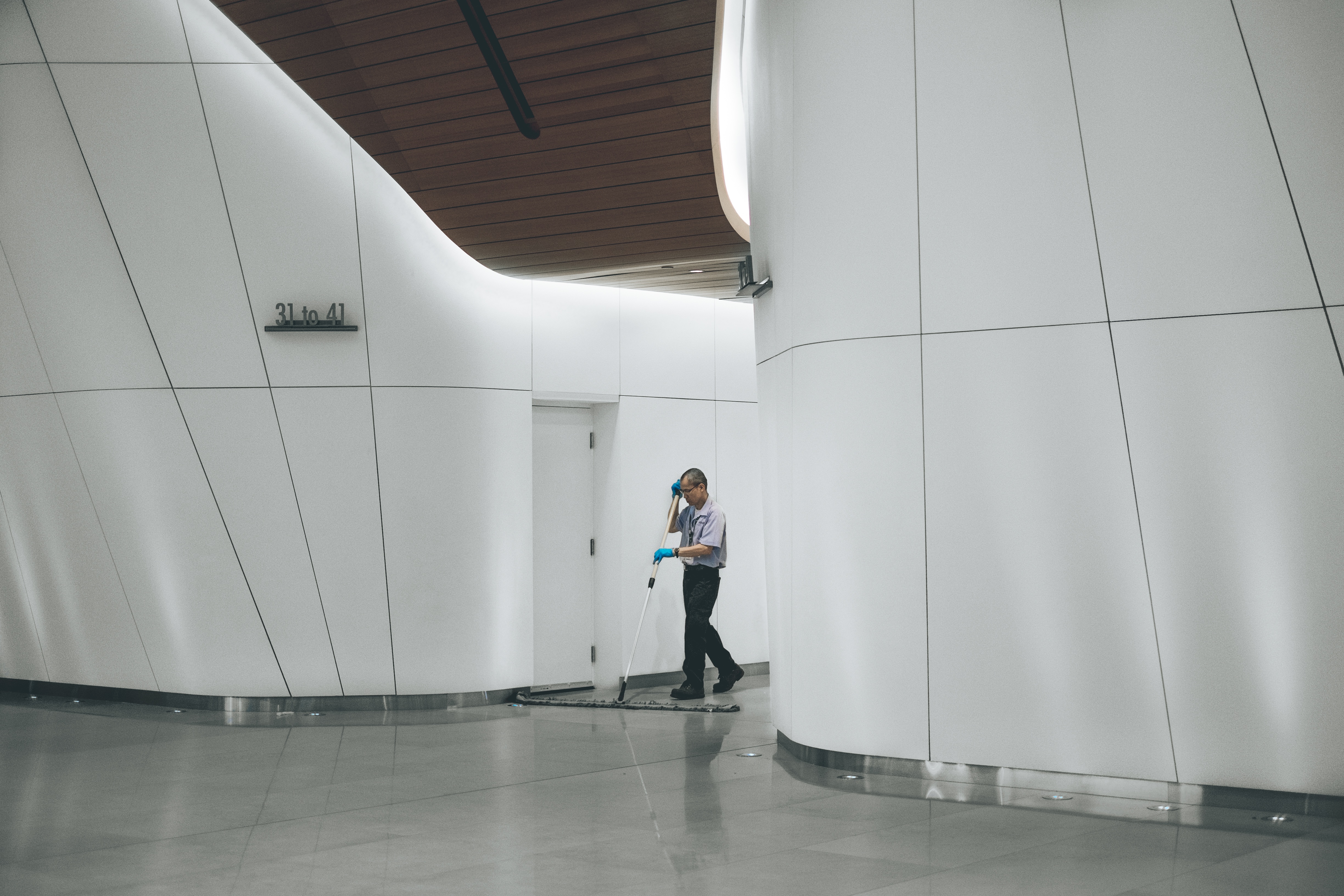 Janitor sweeping floor in modern office building